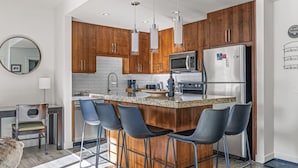 Una cocina moderna con armarios de madera, electrodomésticos de acero inoxidable y taburetes de bar.