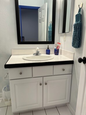 A bathroom with a white sink, black countertop, and white cabinets. There is a mirror above the sink, a blue bottle, and a blue towel hanging on the wall. - Townhouse just outside of Denver (Littleton)