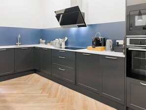 A modern kitchen with dark cabinets, a white countertop, and a built-in oven.