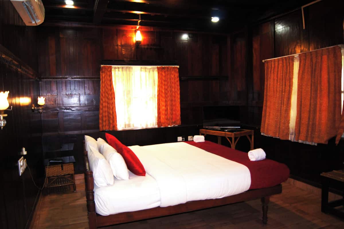 A wooden room with a large bed, a small table, and a television.
