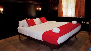 A large bed with white and red bedding, wooden headboard, and two wall-mounted lights.