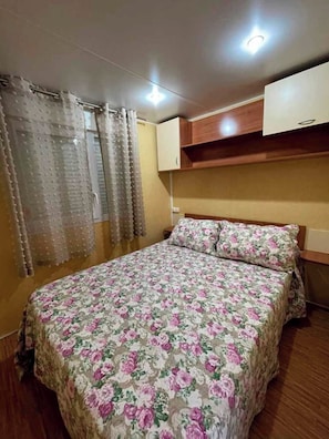 A bedroom with a floral bedspread, wooden headboard, and a ceiling light. - 3-bedroom Super Cute House With Pool (Vejer de la Frontera)