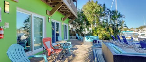 Un patio con mobiliario exterior, piscina y vistas a barcos y palmeras.