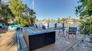 An outdoor patio with a sofa, chairs, and a table, overlooking a marina with boats and a clear sky. - Waterside Retreat! Boutique Condo in Madeira Beach (Madeira Beach)