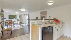 A modern kitchen with white cabinets, a dishwasher, and a dining area with a table and chairs. - 1 Mi to Fanning Springs! Home on Private Acreage (Fanning Springs)
