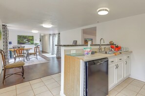 A modern kitchen with white cabinets, a dishwasher, and a dining area with a table and chairs.
