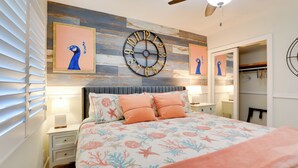 Un dormitorio con una cama, un reloj de pared y un ventilador de techo.