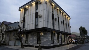 Un bâtiment moderne avec une façade recouverte de carreaux, plusieurs unités de climatisation et une enseigne indiquant qu’il s’agit du Ninety Boutique Hotel.