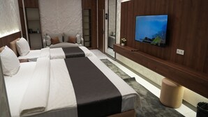Une chambre d’hôtel moderne équipée de deux lits, d’une télévision, d’une petite table et d’un miroir.