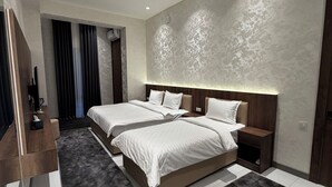 Un dormitorio moderno con dos camas, una mesita de noche de madera, un espejo y un ventanal con cortinas.