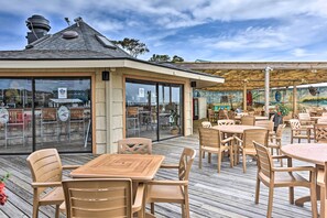 An outdoor patio with wooden tables and chairs, a covered seating area, and a mural on the wall. - Boardwalk to the Beach! Hilton Head Resort Condo (Hilton Head Island)