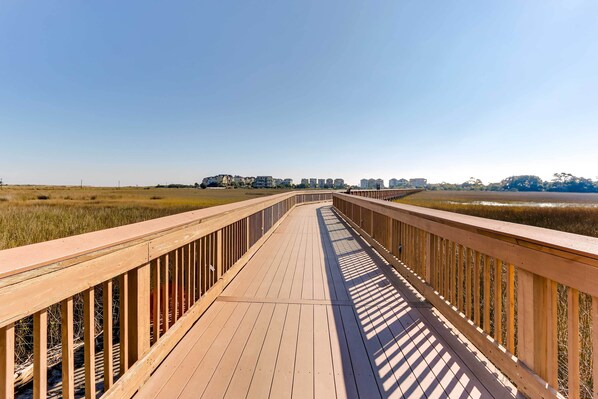 A wooden boardwalk leading to buildings in the distance. - Boardwalk to the Beach! Hilton Head Resort Condo (Hilton Head Island)