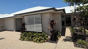 Una casa moderna con garage, una finestra a persiana e un giardino curato.