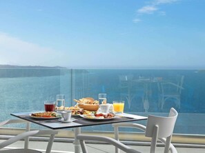 A table with breakfast items and drinks, overlooking a body of water. - Lilium Hotel Santorini (Santorini)