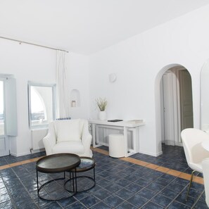 Un salon moderne avec un canapé blanc, une table basse ronde, un bureau blanc et une plante en pot.