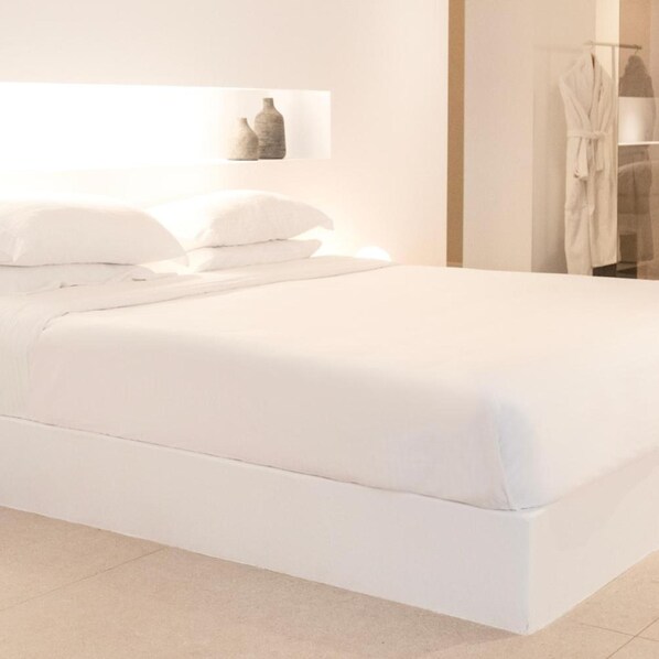 Un lit bien fait, avec du linge de lit blanc, dans une chambre d’hôtel.