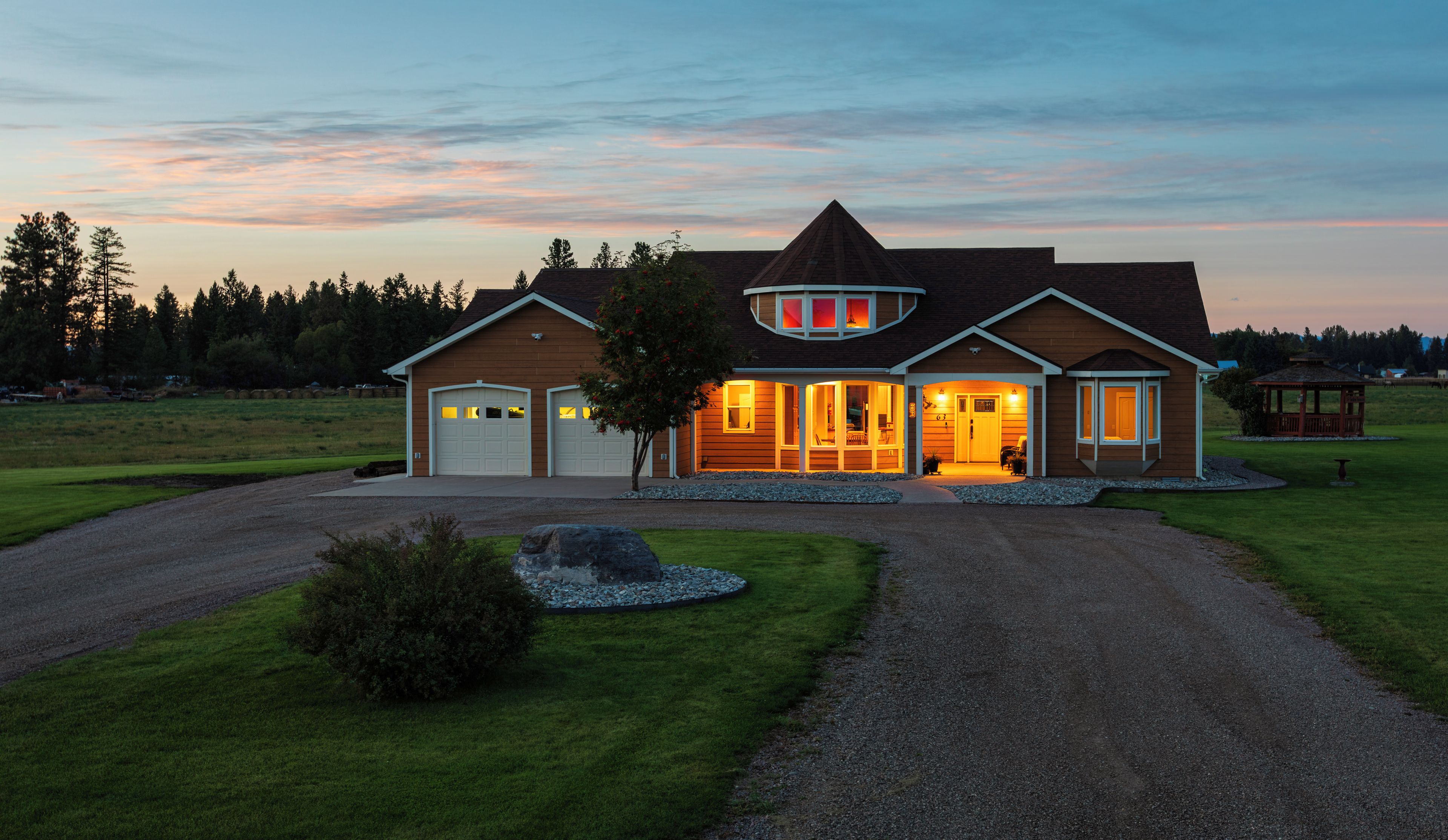 A two-story house with a large garage, a covered porch, and a well-maintained lawn.