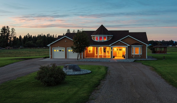 A two-story house with a large garage, a covered porch, and a well-maintained lawn.