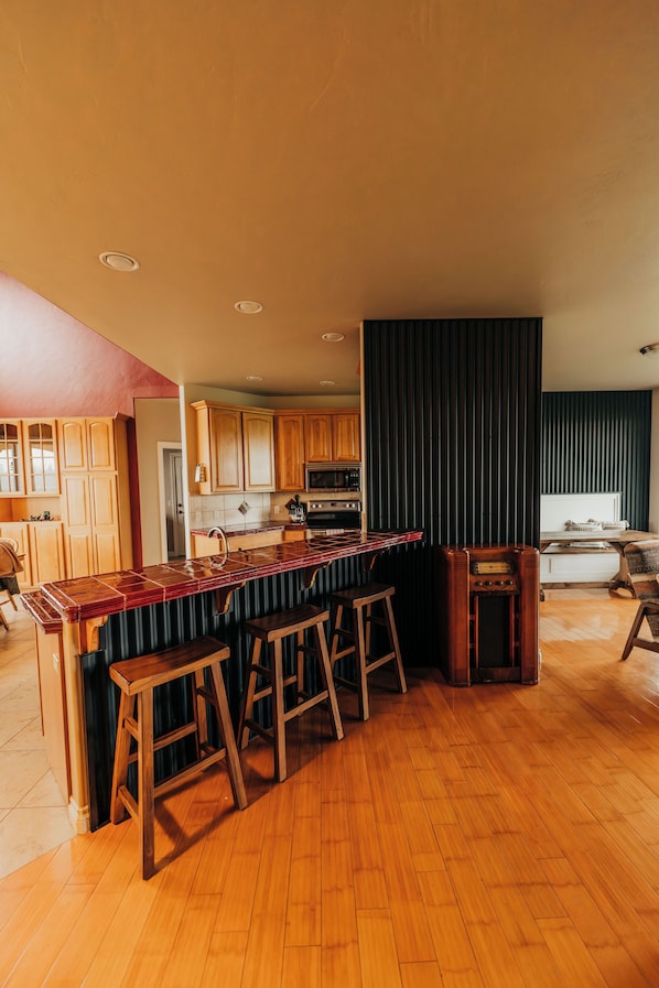 Une cuisine moderne avec des meubles en bois, un coin bar avec des tabourets et un grand îlot central.