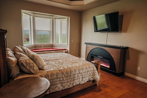 Une chambre à coucher avec un lit, une cheminée, une télévision et une fenêtre donnant sur un beau paysage.