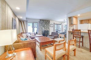 A spacious living room with a fireplace, wooden furniture, and a stone accent wall. - 1 Mi to Village & Eagle Lodge: Condo w/ Fireplace (Mammoth Lakes)