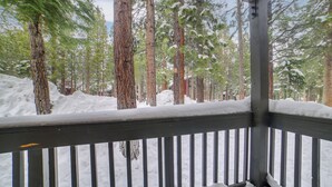 A snow-covered deck with a railing, surrounded by tall evergreen trees. - 1 Mi to Village & Eagle Lodge: Condo w/ Fireplace (Mammoth Lakes)