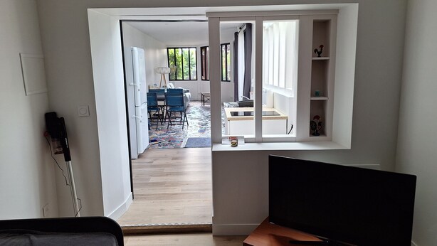 A modern living room with a flat-screen TV, a wooden coffee table, and a dining area with a table and chairs. - Accommodation in the Heart of the Nantes Vineyard - Near Clisson (Mouzillon)