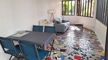 Um interior moderno com uma mesa de jantar, cadeiras, um sofá e um chão com azulejos coloridos e refletivos.
