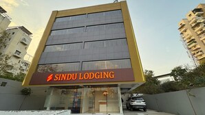 A modern building with a sign reading "SINDU LODGING". - Sindu Executive Lodging (Pune)