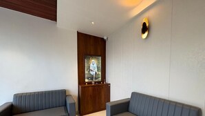 A modern living room with two grey sofas, a wooden cabinet, and a stone wall. - Sindu Executive Lodging (Pune)