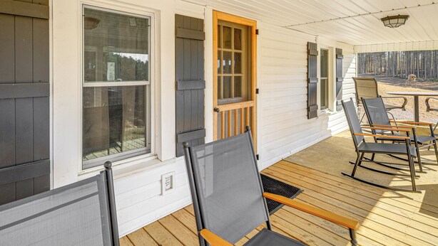 A covered porch with wooden flooring, a table, and several chairs. - Mtn Views, New River Access & 98 Acres: Galax Gem (Galax)