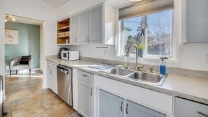 A modern kitchen with white cabinets, a stainless steel sink, and a window with blinds. - 4 Mi to Riverwalk & CSU Pueblo! Home w/ Sunroom (Pueblo)