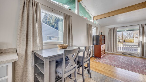 A dining area with a table and chairs, a television on a wooden cabinet, and a view of the outside through large windows. - 4 Mi to Riverwalk & CSU Pueblo! Home w/ Sunroom (Pueblo)