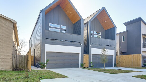 A modern two-story house with a garage, a wooden deck, and a small yard. - Near NRG Stadium & Med Center | Group Retreat (Houston)