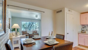 A dining area with a wooden table set for four, white plates, and a white lamp. - Hike, Golf & Dine: Tucson Retreat w/ Mtn Views! (Tucson)