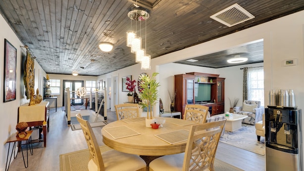 A spacious living area with a round wooden dining table, multiple chairs, and a modern kitchen in the background. - Explore Historic Dtwn Punta Gorda! Home w/ Deck (Punta Gorda)