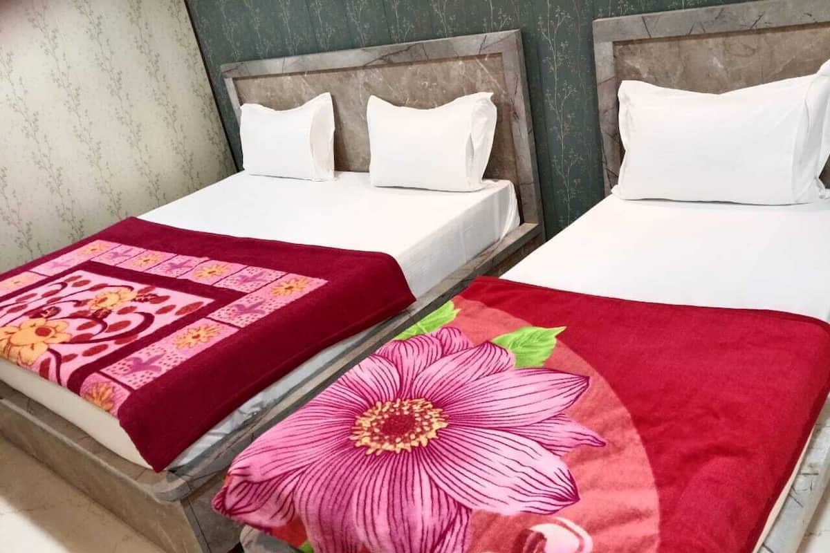 Deux lits avec du linge de lit blanc et des couvre-lits à motifs floraux rouges.