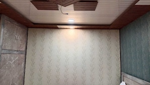 A bathroom with a wooden ceiling, patterned wallpaper, and a white towel on the wall. - Hotel Tulsi Palace (Jaipur)
