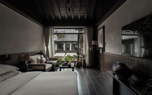 Una habitación de hotel con cama, sofá, una mesita y una ventana con cortinas.