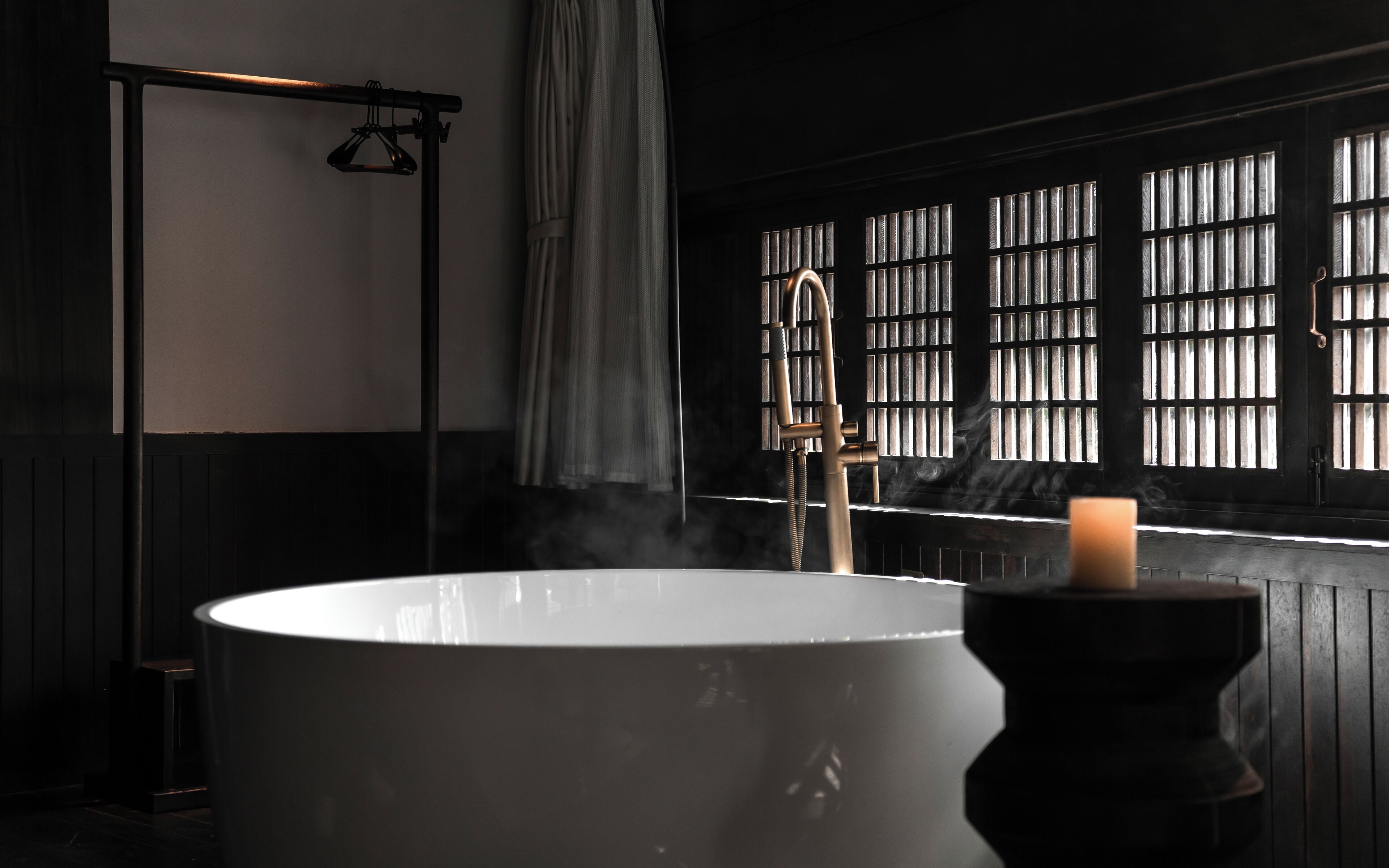 Un baño moderno con una bañera grande, un perchero para toallas y una ventana con barrotes.