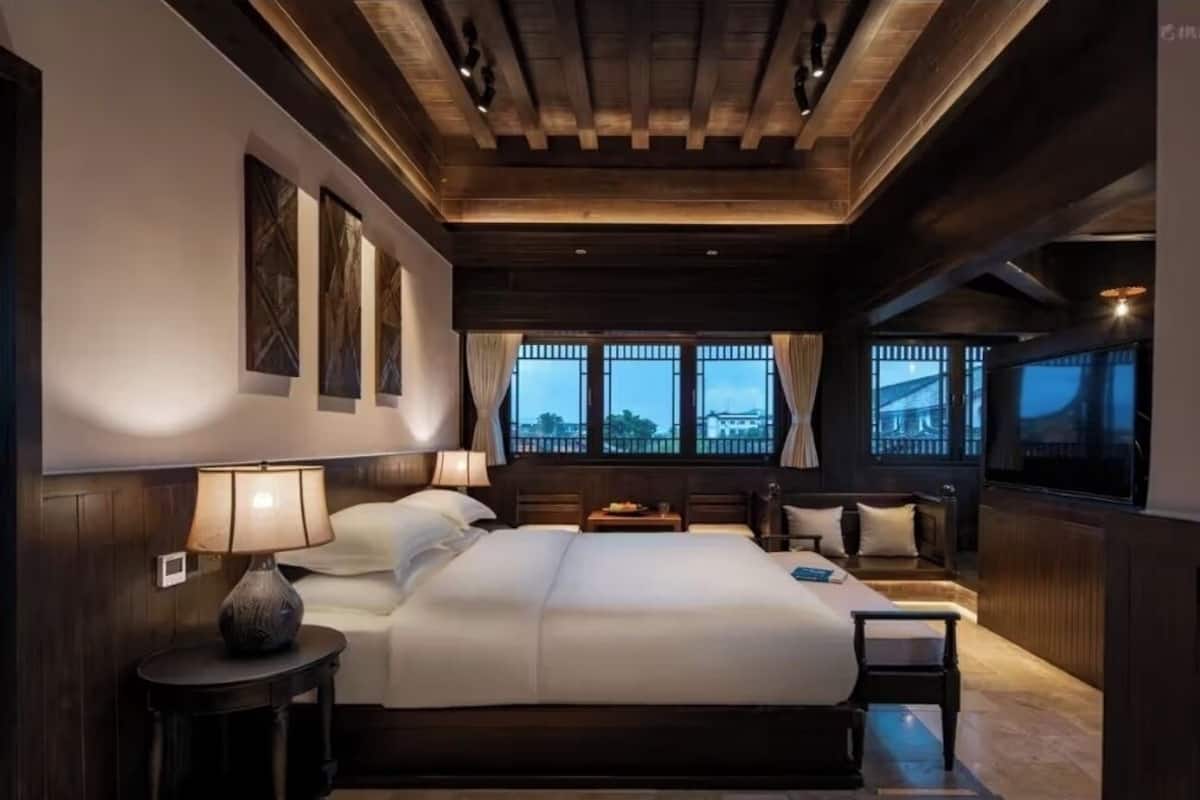 Um quarto espaçoso com uma cama grande, mesas de cabeceira e vista para o exterior através de amplas janelas.