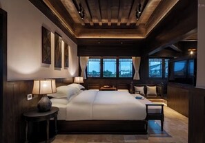 Um quarto espaçoso com uma cama grande, mesas de cabeceira e vista para o exterior através de amplas janelas.