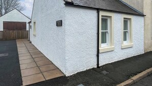 Una casa blanca de dos pisos con entrada pavimentada y garaje.