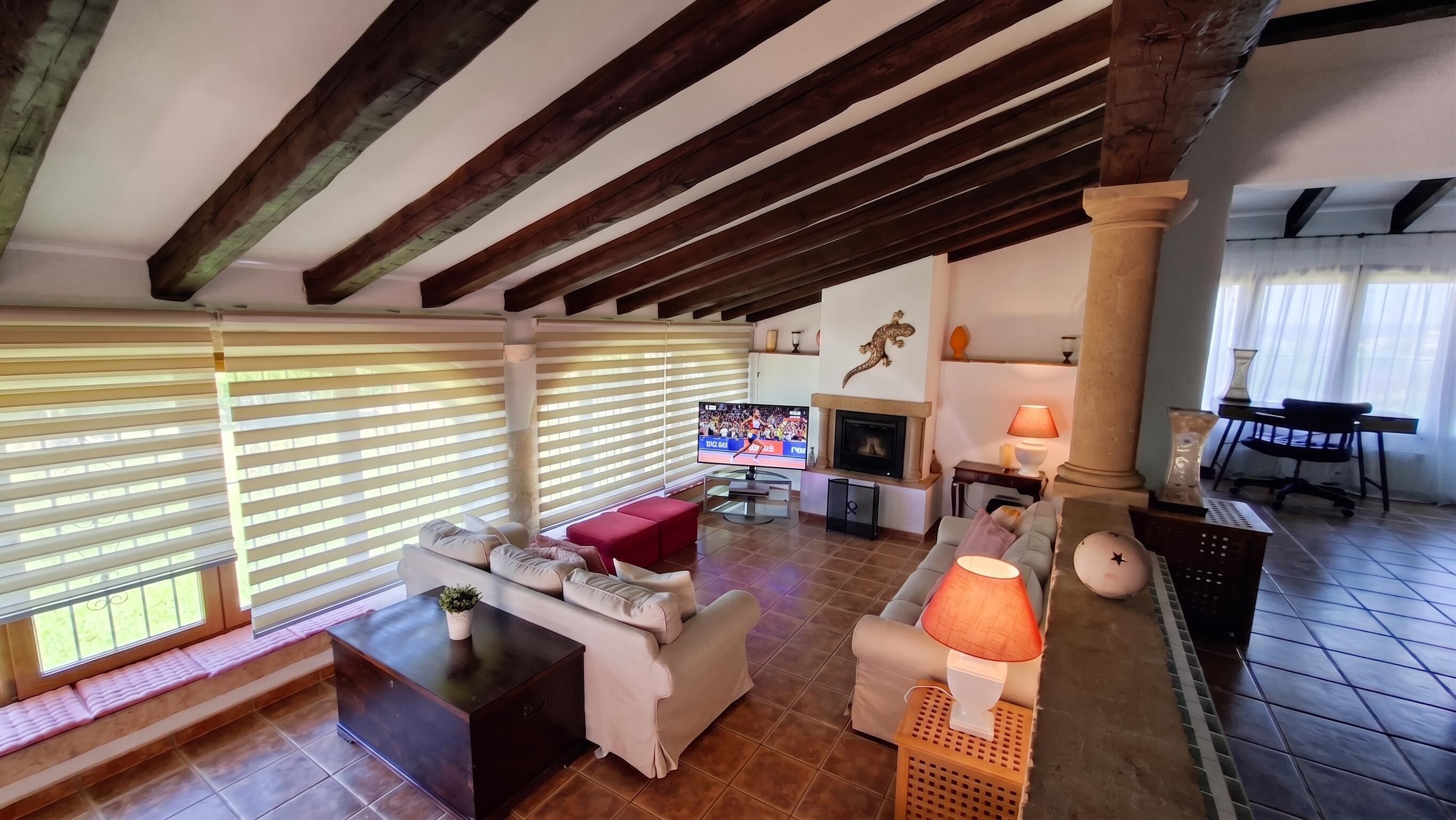 A living room with a fireplace, a television, and a seating area with a lamp.