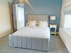 Une chambre à coucher avec un lit, une table de chevet et une fenêtre.