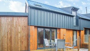 A modern building with a wooden exterior, large sliding glass doors, and a deck with outdoor furniture. - Arenig View - UK51068 (Rhyd Uchaf Nr Bala)