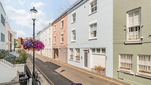 En smal gata kantad av höga byggnader, var och en med en distinkt arkitektonisk stil och en mängd olika fönsterdesigner.