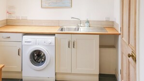 A compact kitchen with a washing machine, a sink, and a map on the wall. - Spacious house sleeping ten, perfect for large families or groups. (Pembroke)
