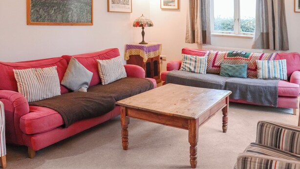 A living room with two sofas, a coffee table, and a lamp. - Spacious house sleeping ten, perfect for large families or groups. (Pembroke)