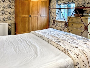 A bedroom with a wooden wardrobe, a window with a view, and a bed with a floral bedspread. - 3 bedroom accommodation in Bradford Abbas (Bradford Abbas)